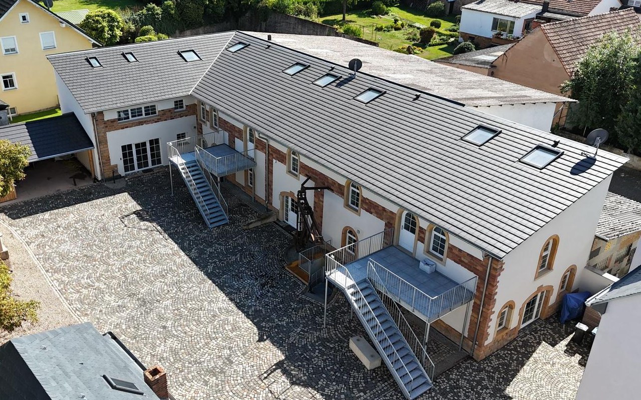 Großes Ziegeldach eines umgebauten Hofgebäudes mit zwei Reihen Dachflächenfenstern